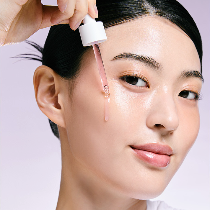 Woman applying JUMISO Niacinamide 20 Serum 40ml on her face for glowing skin.