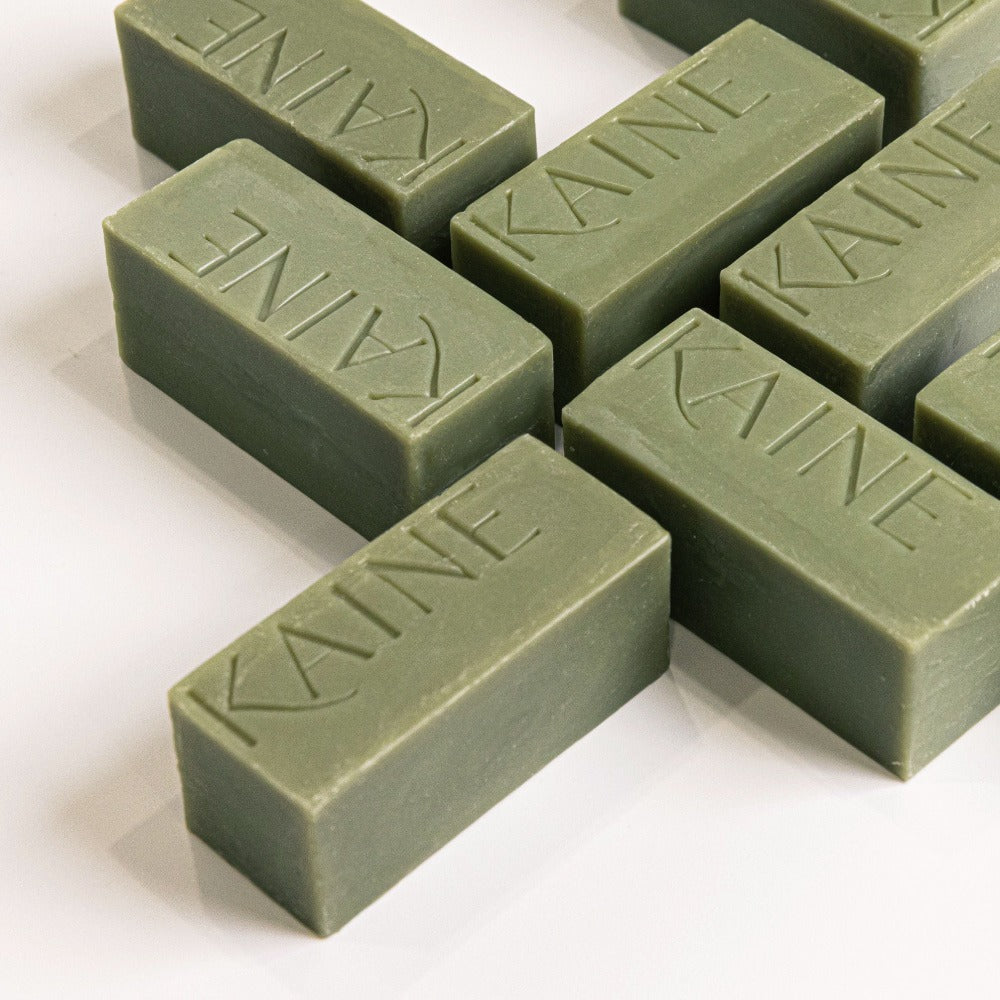 Image of multiple green bars of KAINE Rosemary Acne Mildly Acidic Cleansing Bar 100g, arranged on a white surface.