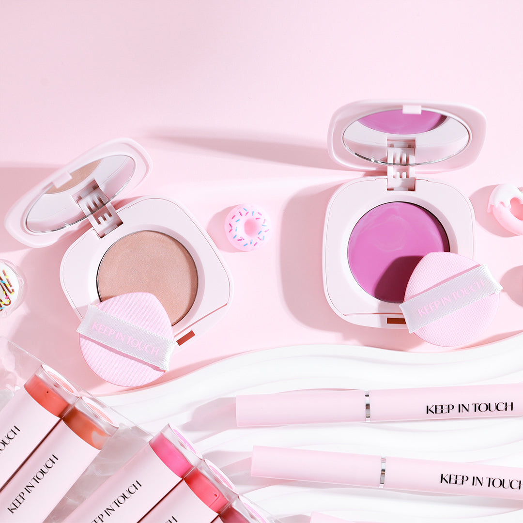 KEEP IN TOUCH GLossy Glow Marine Balm in open containers, showcasing vibrant shades and sleek packaging on a pink background.