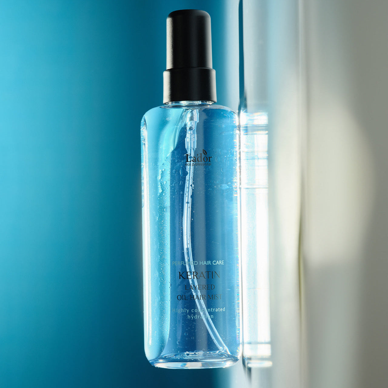 LADOR Keratin Perfume Hair Mist 130ml bottle with blue liquid on reflective surface