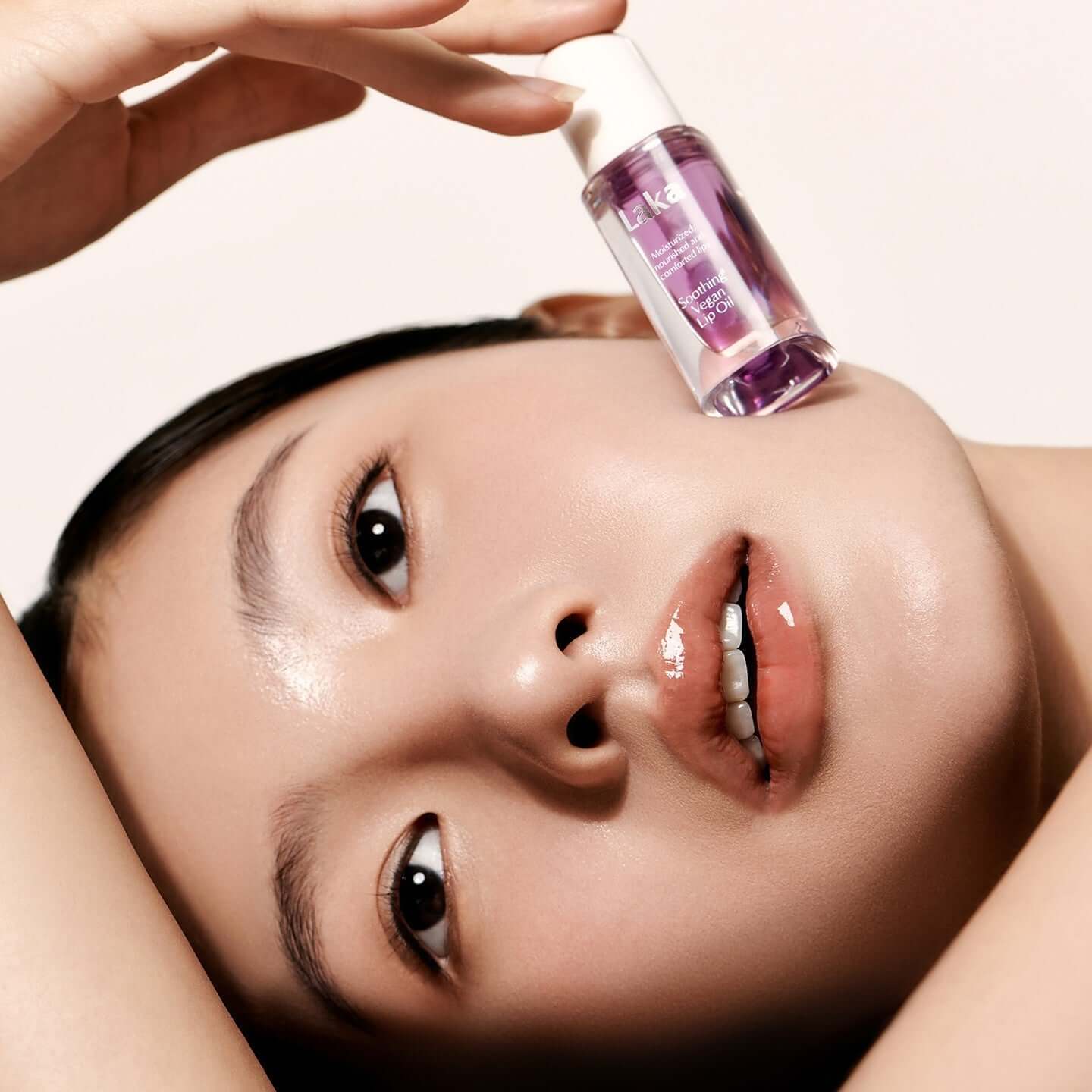Model with LAKA Soothing Vegan Lip Oil against her face showcasing glossy lips and smooth skin.