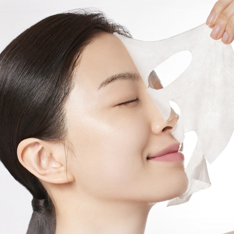 Woman applying MAMONDE Age Control Camellia Ampoule Mask Pack on her face for skincare routine.