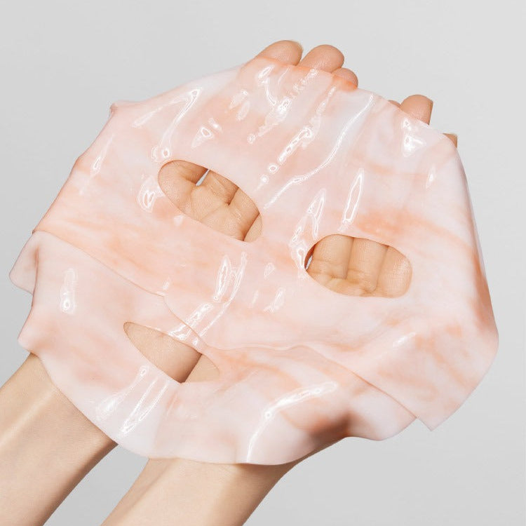 Hands holding MAMONDE Flora Glow Rose Marble Pack sheet mask showcasing its texture and color.