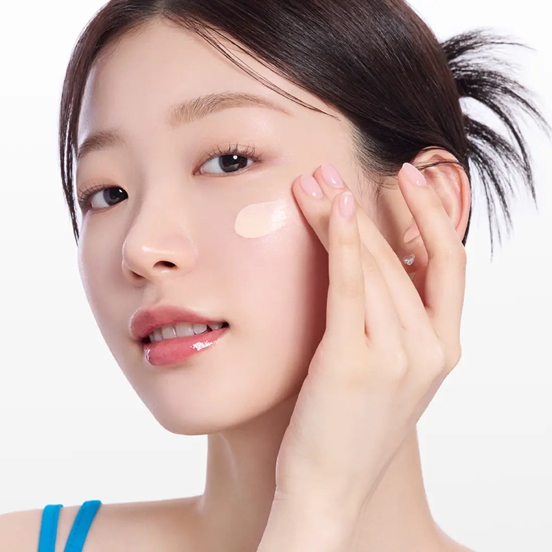 Woman applying MAMONDE NEW Floraglow Rose Tinted Sun Serum 35ml on her cheek to demonstrate skincare routine.