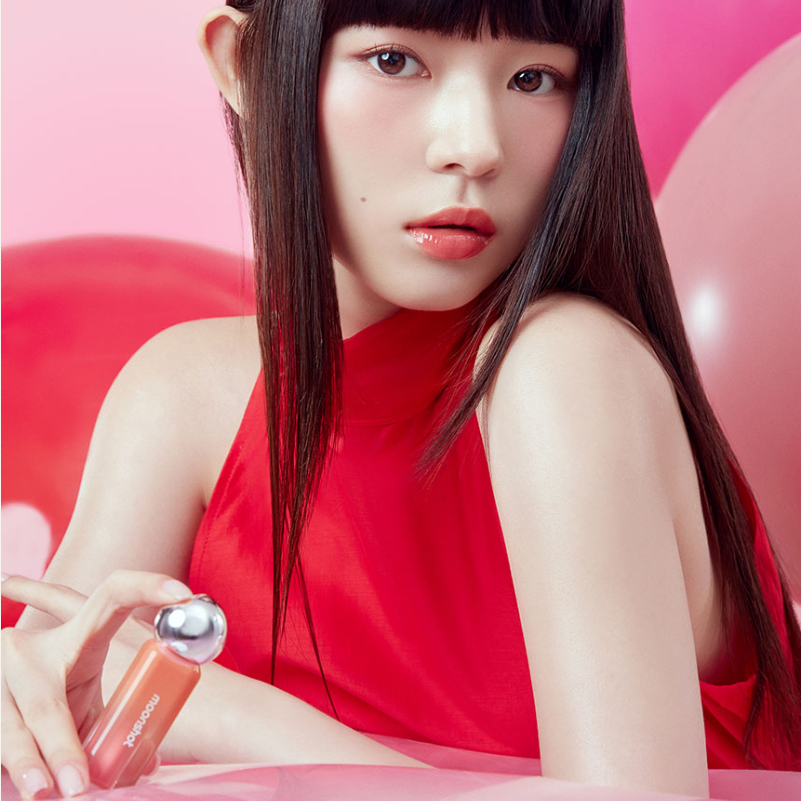 Model showcasing MOONSHOT Jelly Moon Glow Tint in a vibrant red setting, highlighting the product's glossy finish.