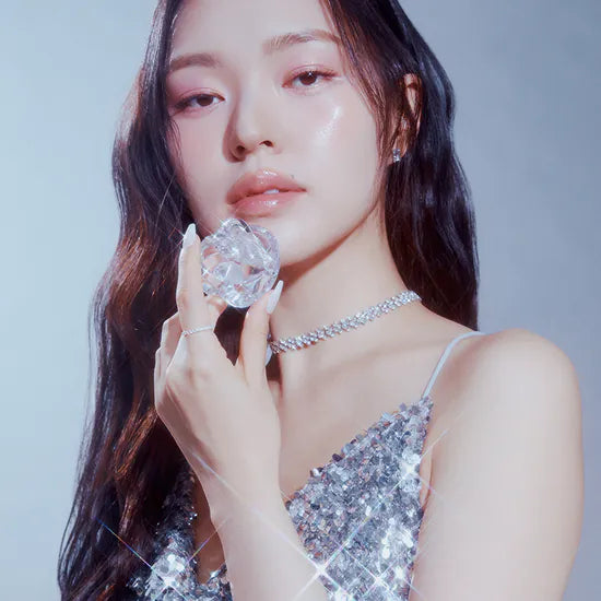 Woman holding crystal, wearing shimmering dress in elegant pose.