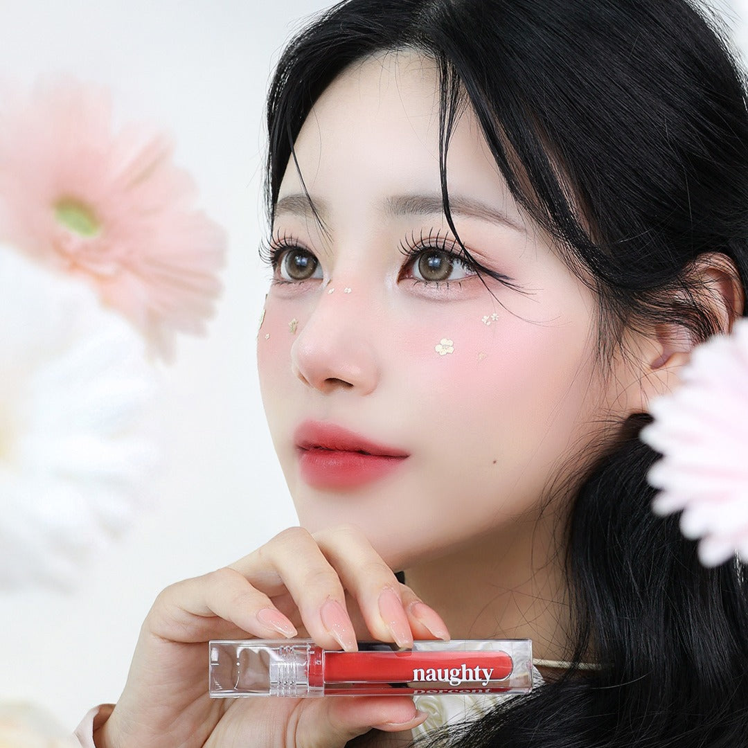 Woman holding NAUGHTY PERCENT Matte Bloom Tint with floral background