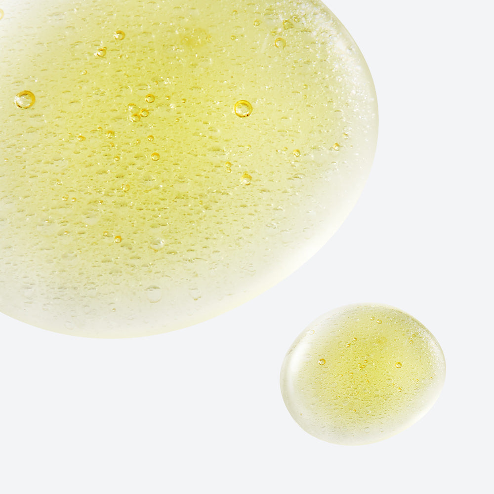 Close-up view of the texture of NEOGEN White Truffle Ampoule Drop Mist 80ml showing yellow droplets and bubbles.
