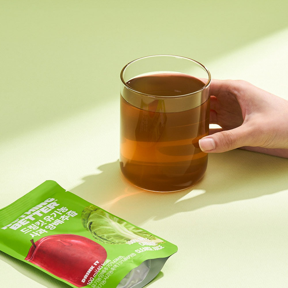 NOTHING BETTER Drinkit Organic Applr Cabbage Juice 100ml 24 Packets with a glass of juice and packet on a table.
