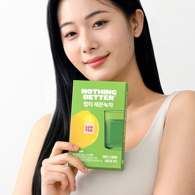 Person holding NOTHING BETTER Luv Tea Lemon Green Tea (X15) package, promoting lemon-flavored green tea in vibrant packaging.