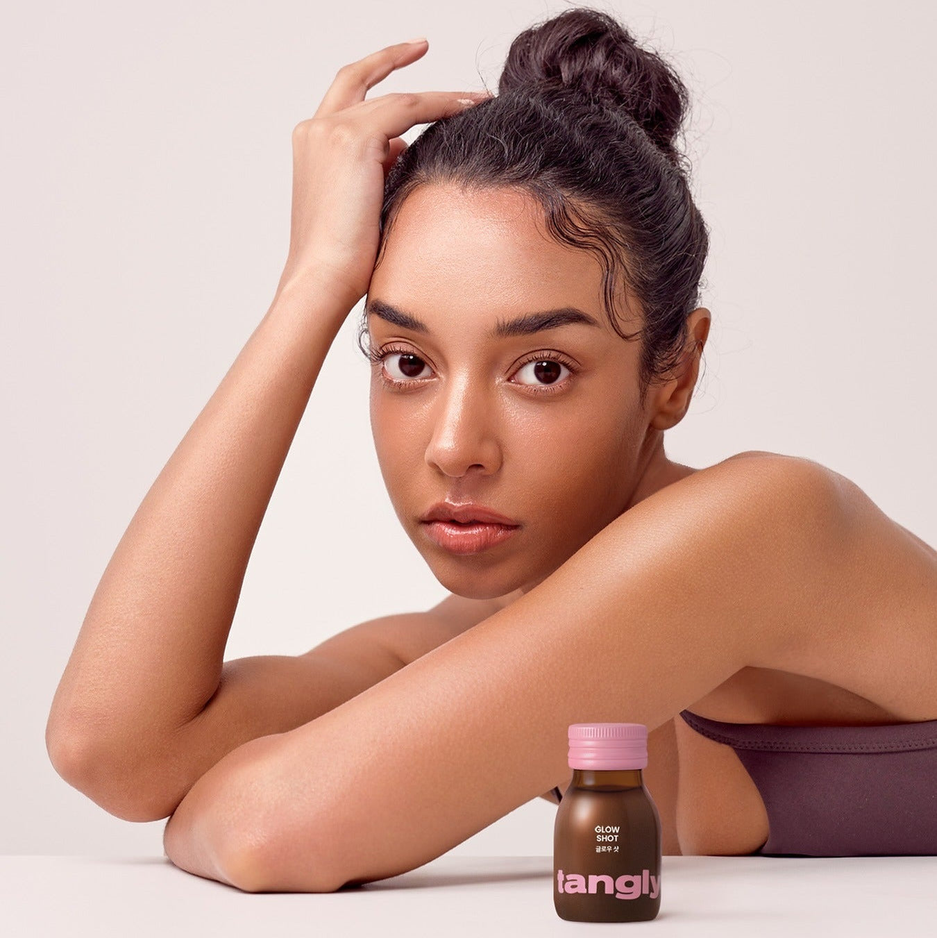 Woman next to NOTHING BETTER Tangly Glow Shot 7 Bottles, highlighting skincare benefits of the Tangly Glow product shot.