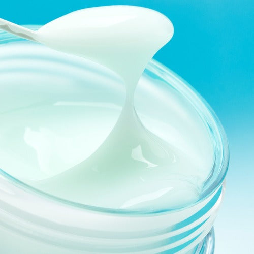 Open jar of creamy texture, NUMBUZIN No.1 Pantothenic Acid Active Soothing Cream 80ml, with a spoon dipped into the product against a blue background.