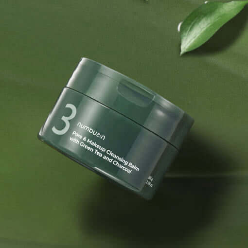 NUMBUZIN No.3 Green Tea Charcoal Pore Pack Cleansing Balm in green container on a leafy background.
