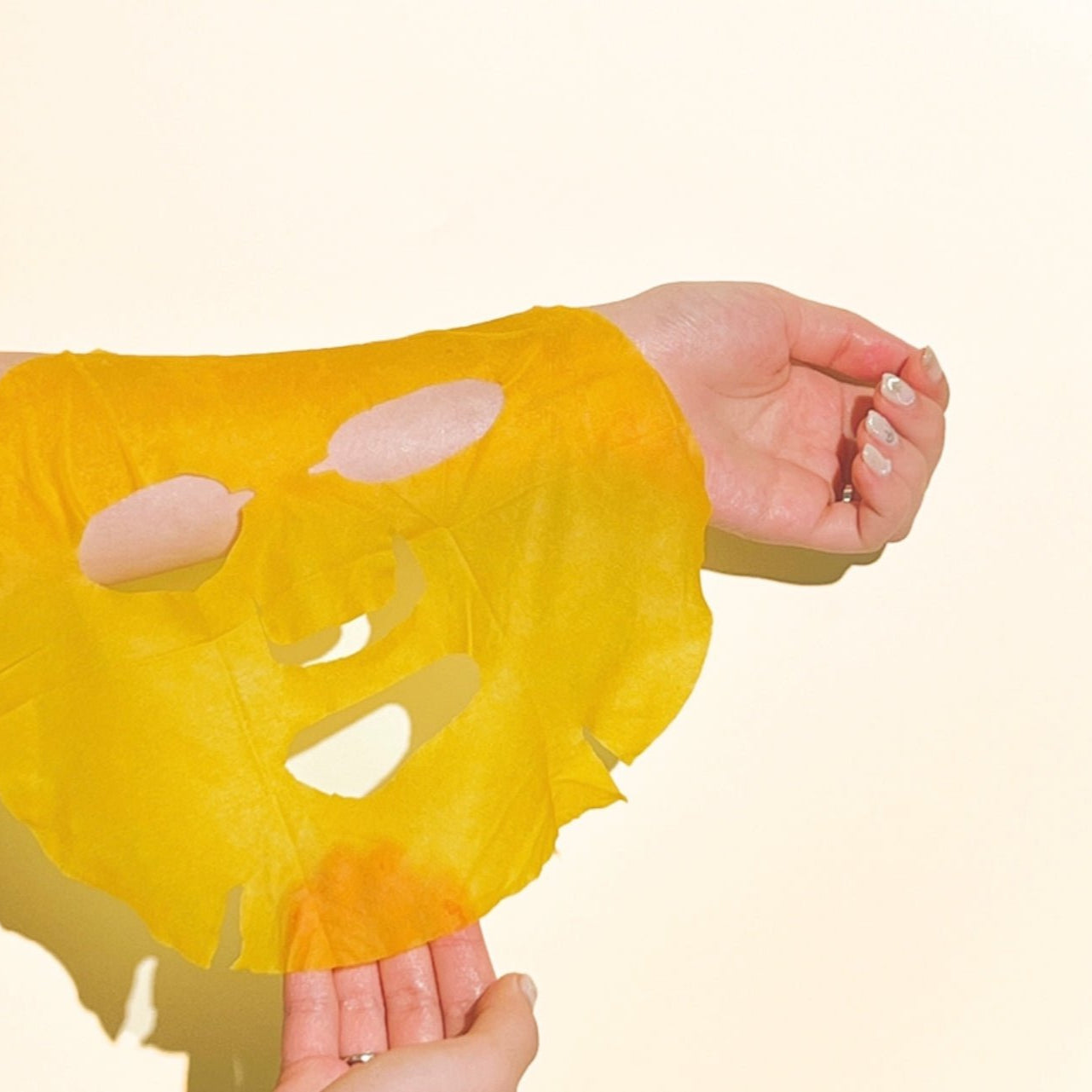 Hands holding NUMBUZIN No.5 Vitamin Spotlight Sheets Mask in yellow against a light background.