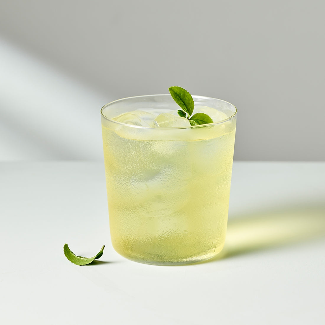 Glass of iced OSULLOC Jeju Pure Green Tea 20 P with mint leaves on white table