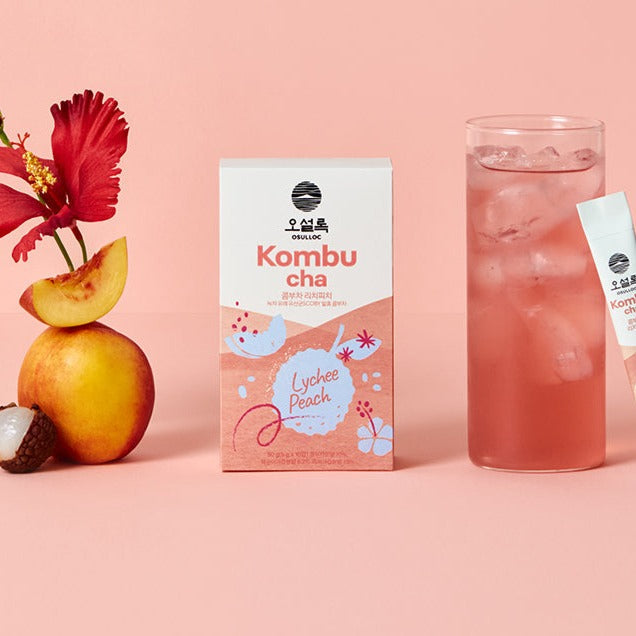 OSULLOC Kombucha Lychee Peach flavor with glass, peach, and hibiscus on a pink background.