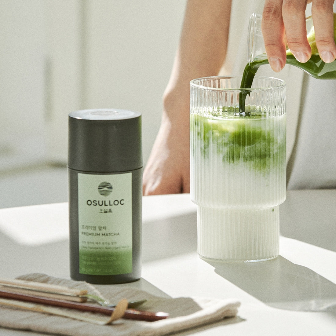 OSULLOC Premium Matcha 40g next to glass of matcha drink on a table