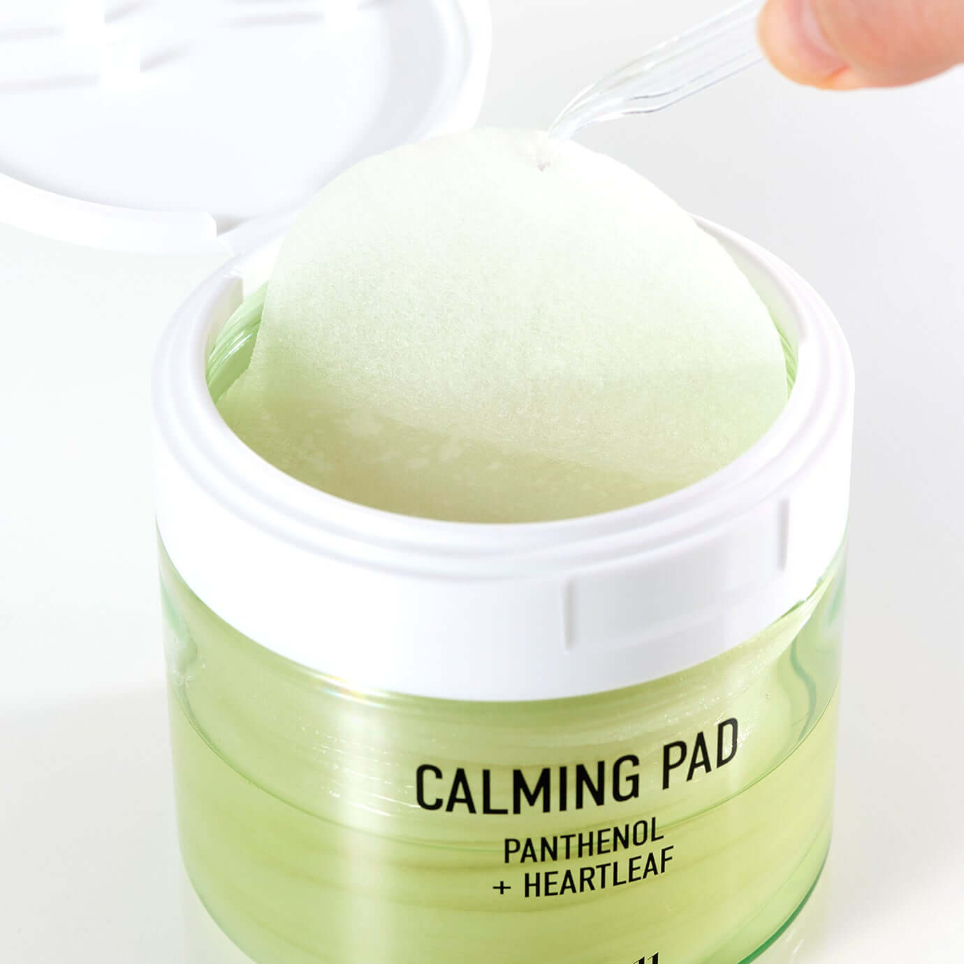 PARNELL Panthenol Heartleaf Calming Pad 60pads being picked with a tool from an open jar, showcasing product design and texture.