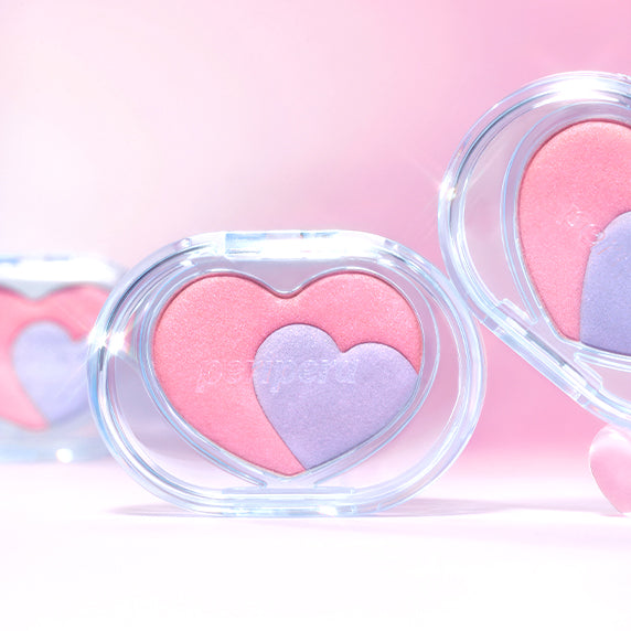 PERIPERA Heart Pocket Beam makeup in heart-shaped compact with pink and purple shades against a soft pink background.
