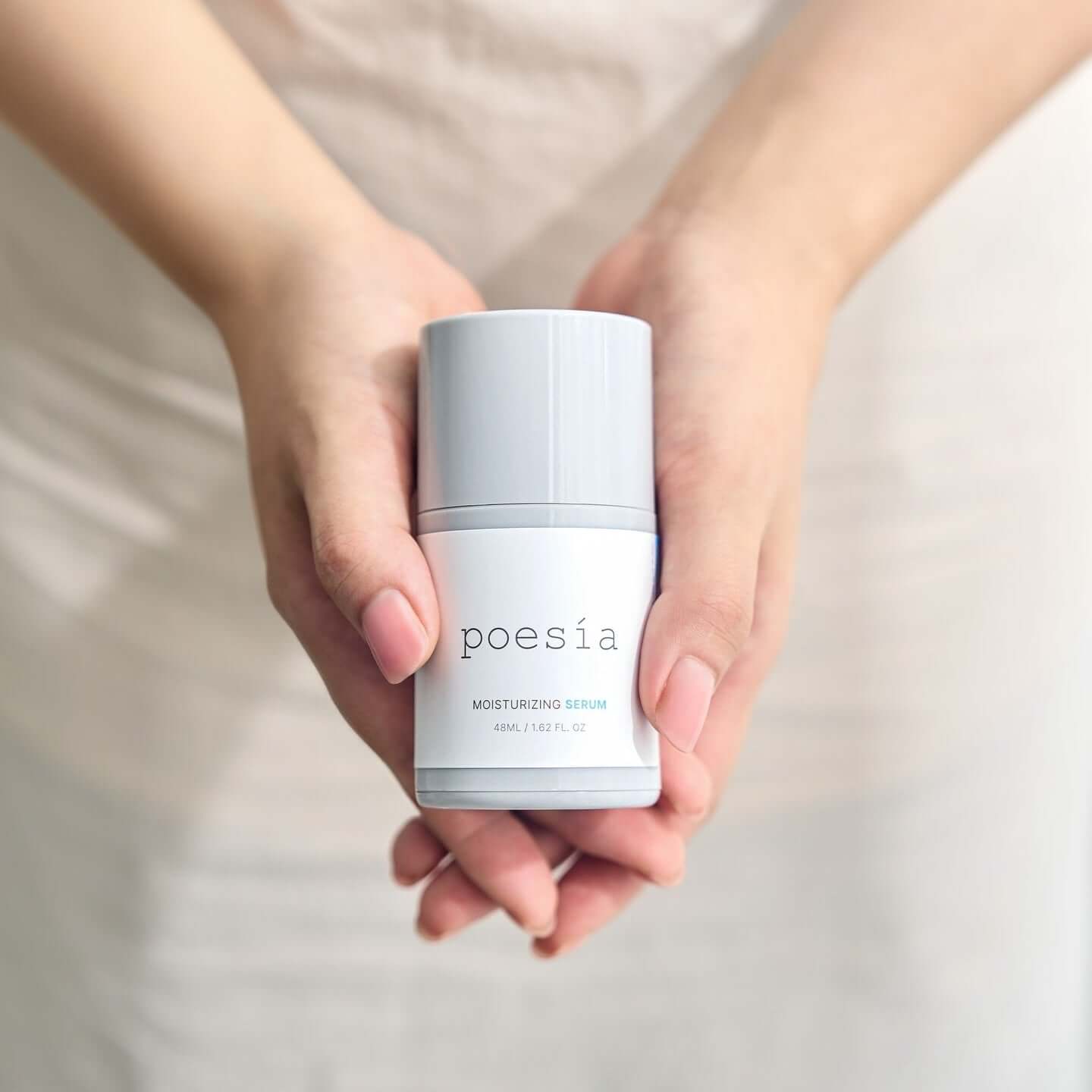 Hands holding POESÃA Hydro Hyaluronic Deep Moisturizing Ampoule Serum 48ml bottle.