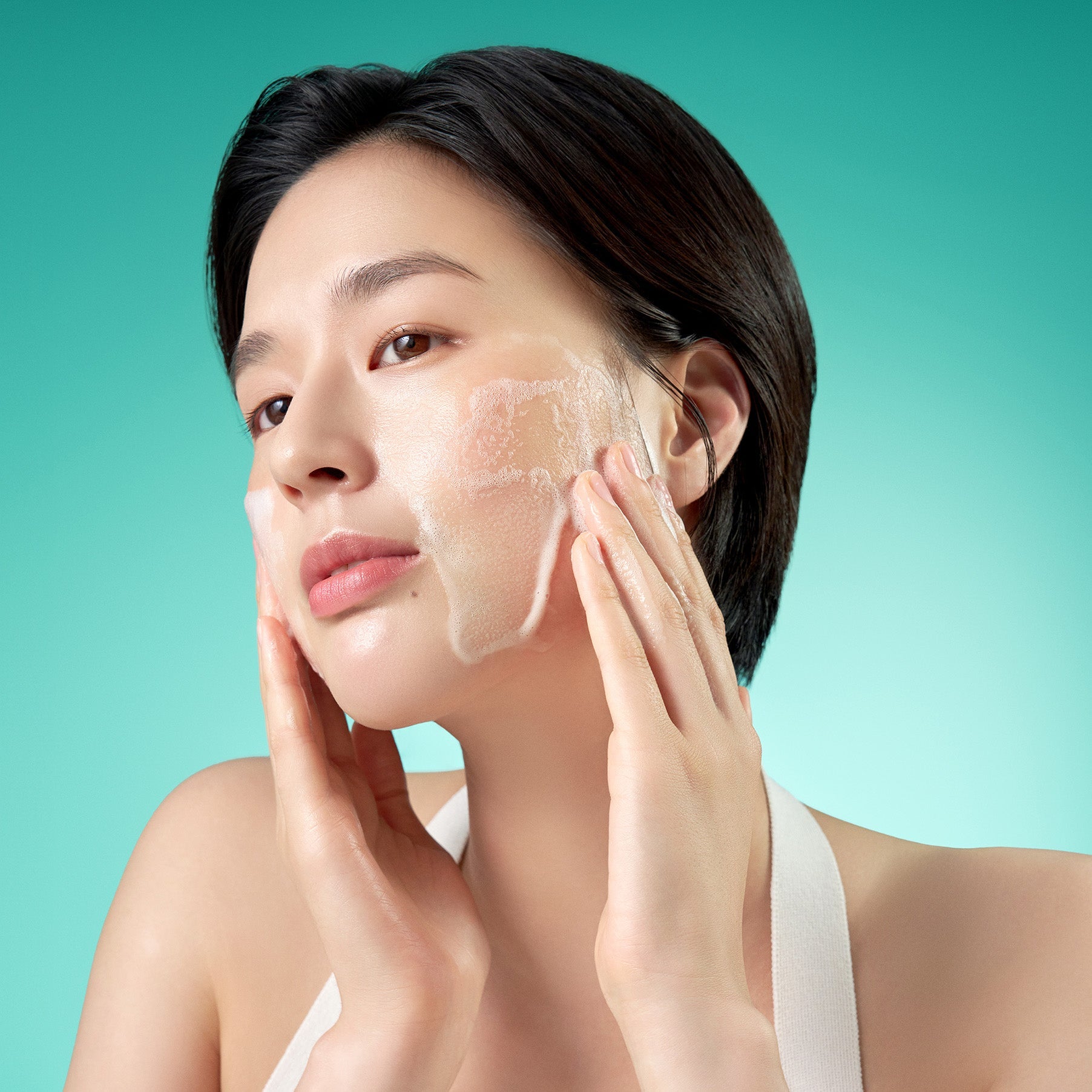 Woman using PURITO Mighty Bamboo Panthenol Cleanser 150ml, demonstrating lathering on skin for skincare routine.