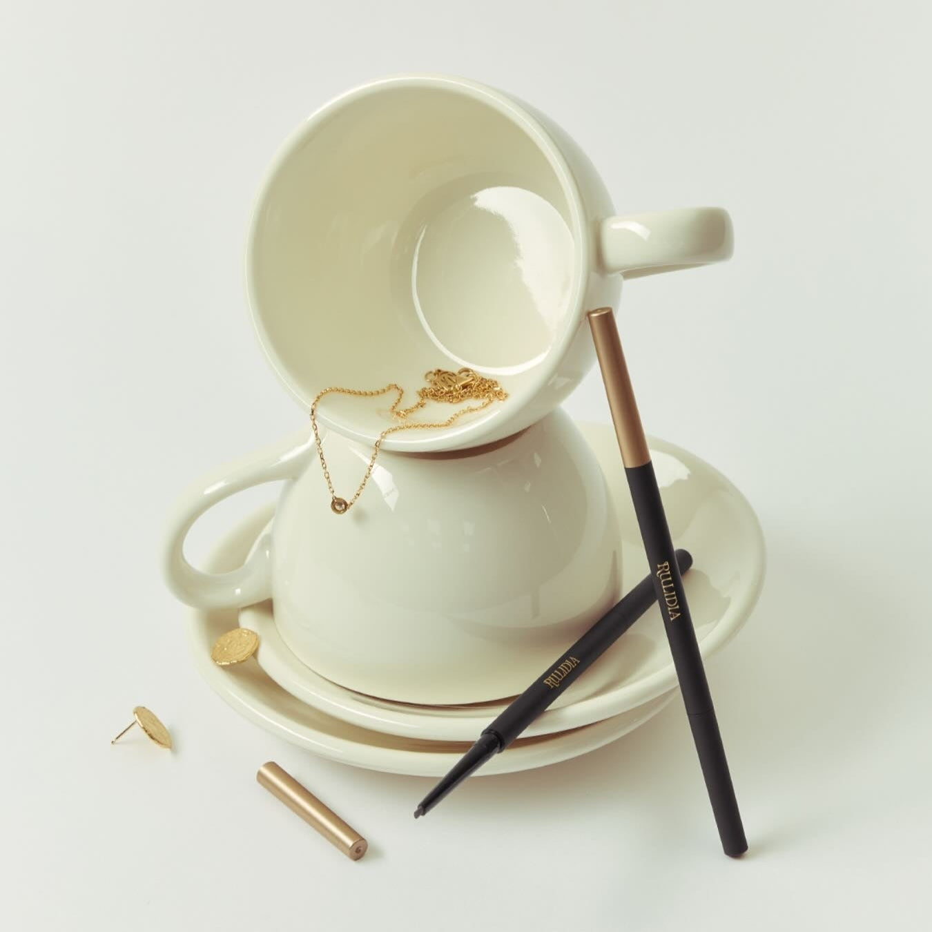 RULIDIA Easy Detail Brow pencil displayed creatively with a ceramic cup and saucer, highlighting its precision and design.