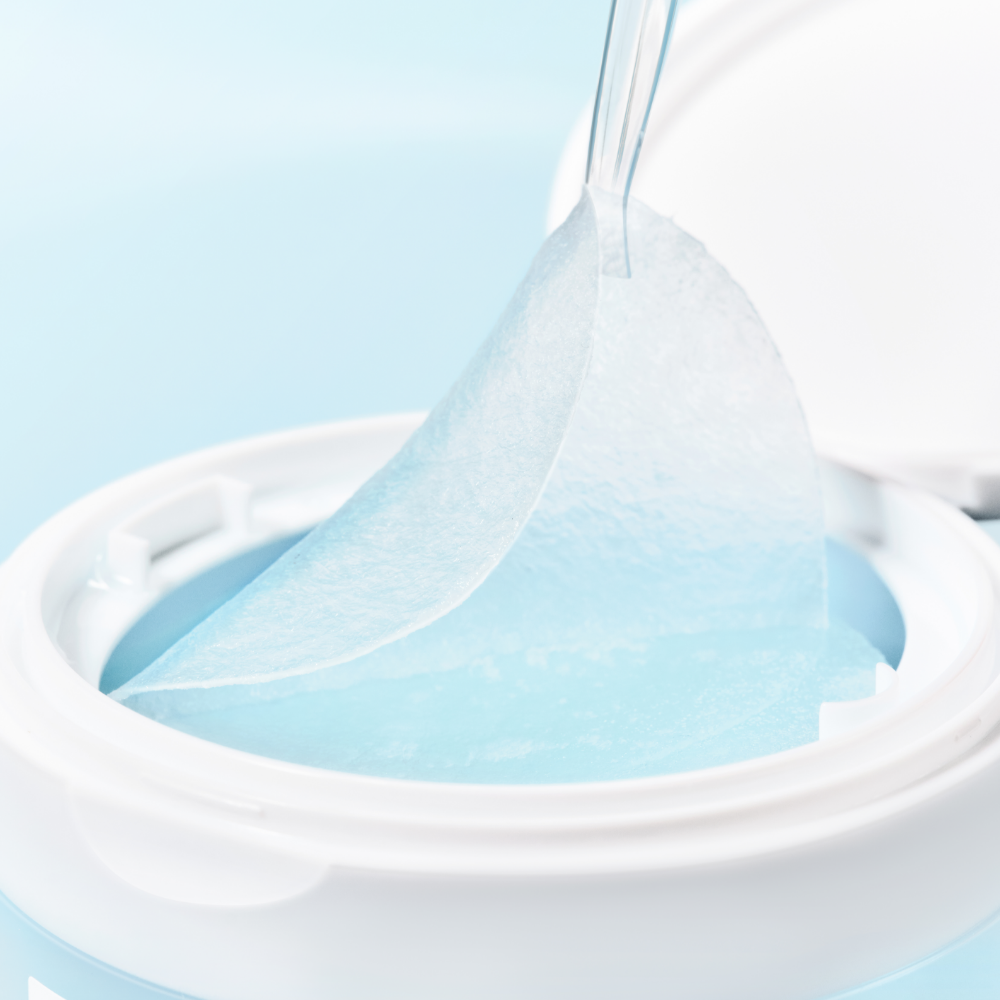 Close-up of SKIN1004 Madagascar Centella-Hyalu-Cica Jelly Fit Ampoule Pads (60 sheets) in a white container with a pad being removed.