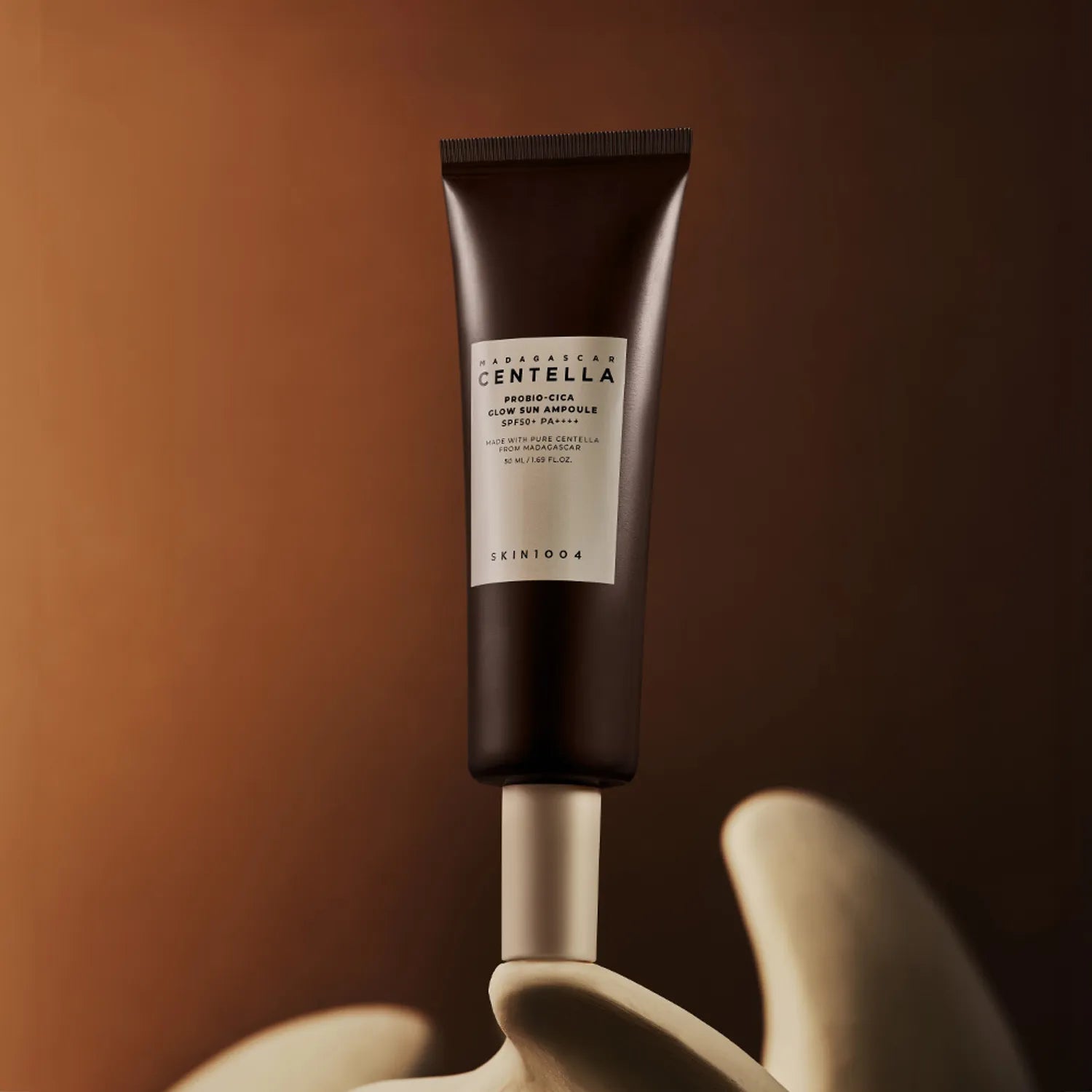 SKIN1004 Madagascar Centella Probio-cica Glow Sun Ampoule 50ml on display against a warm backdrop