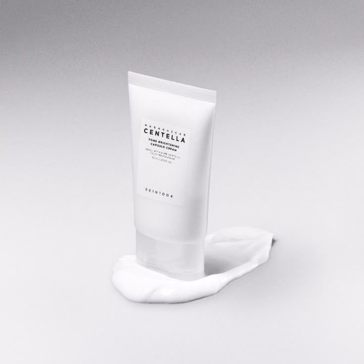 SKIN1004 Madagascar Centella Tone Brightening Capsule Cream 75ml in white tube on gray background showing creamy texture.