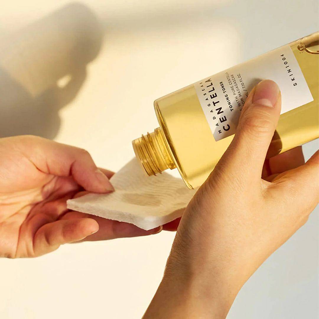 Pouring SKIN1004 Madagascar Centella Toning Toner 400ml onto a cotton pad.