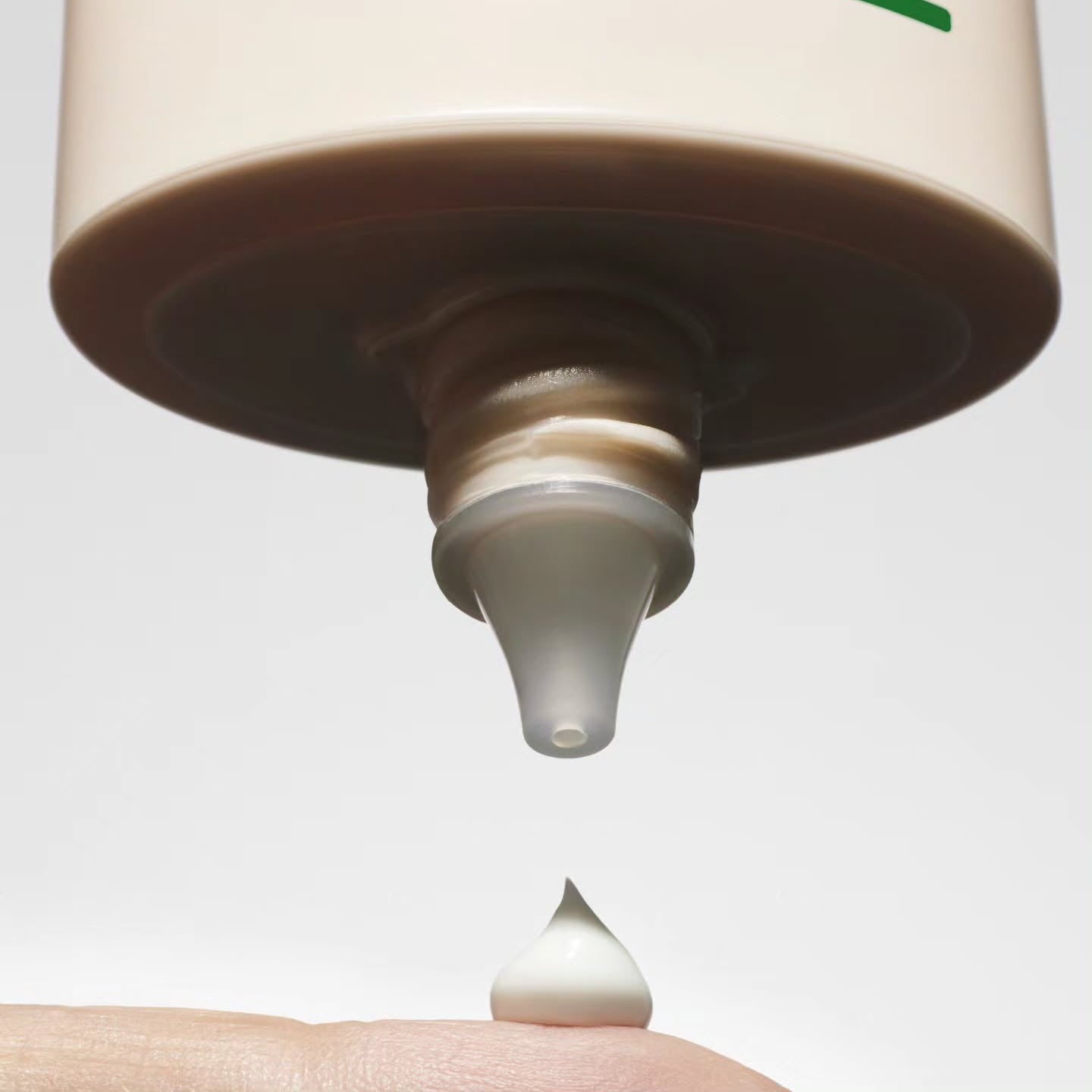 Close-up of TALITHA KOUM To go Essence Sun Screen 60ml being dispensed onto a finger, highlighting its creamy texture and packaging.