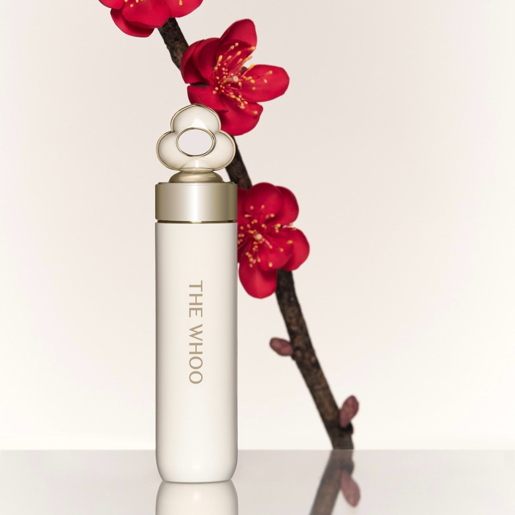 Elegant packaging of THE WHOO Essentail Lip Glow Balm with red flowers in background.