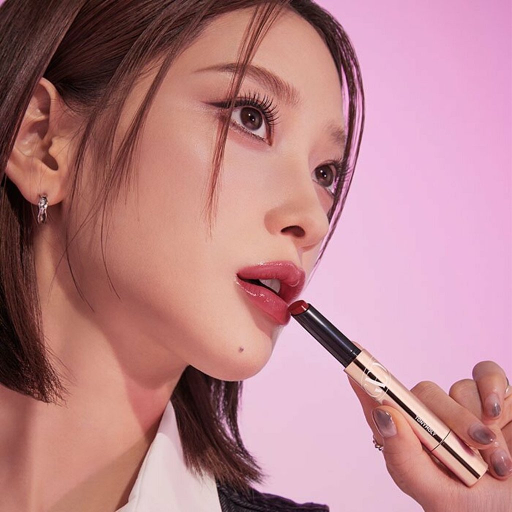Woman applying TONY MOLY Get It Tint Glaze Balm on lips against pink background