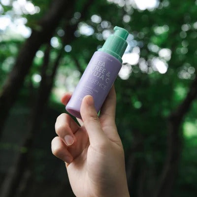 Hand holding TONYMOLY Pure Tea Tree & Yuzu Seed Vitality Essence 50ml bottle outdoors