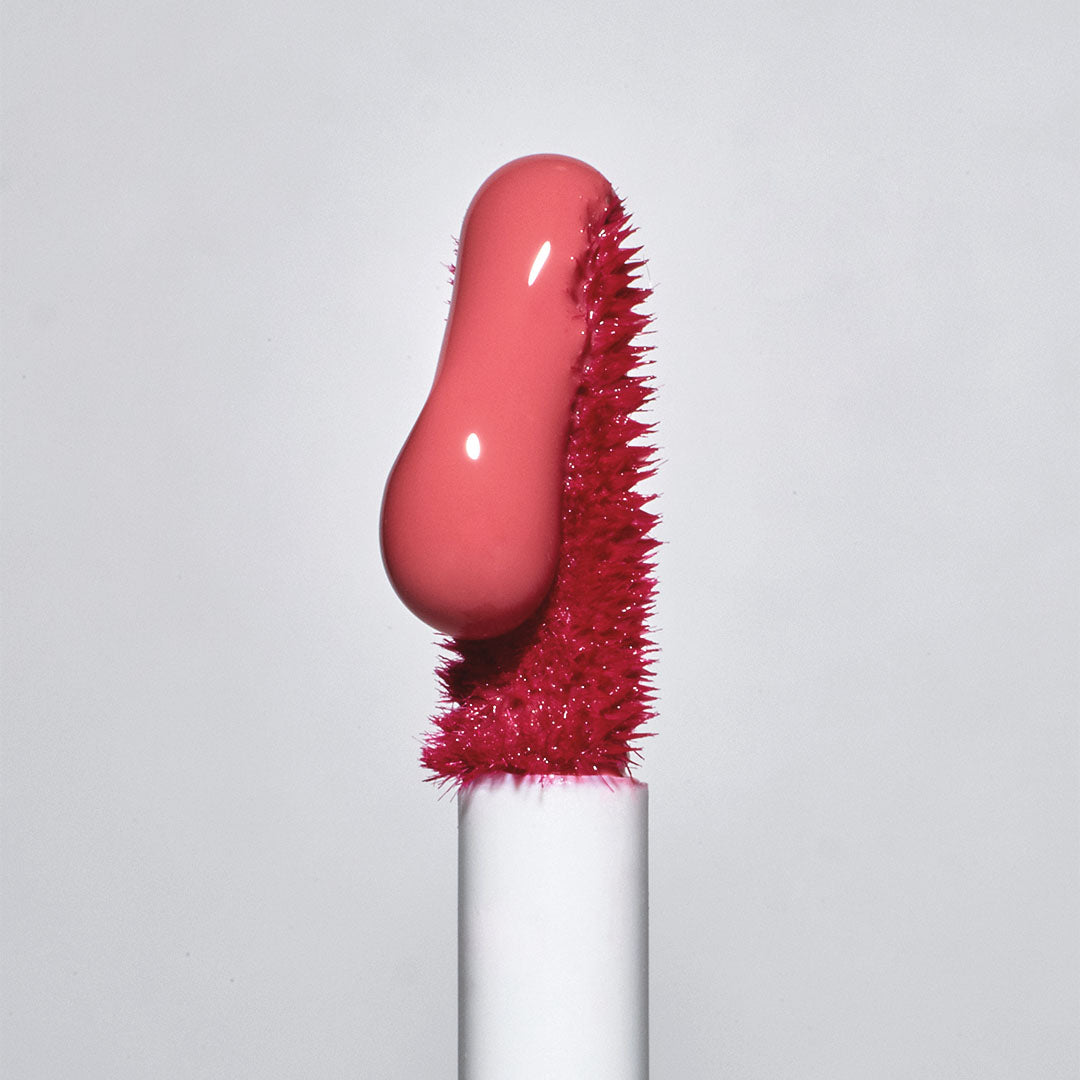 Close-up of TOOQ Gentle Kiss Glow Tint applicator with vibrant pink tint on brush.