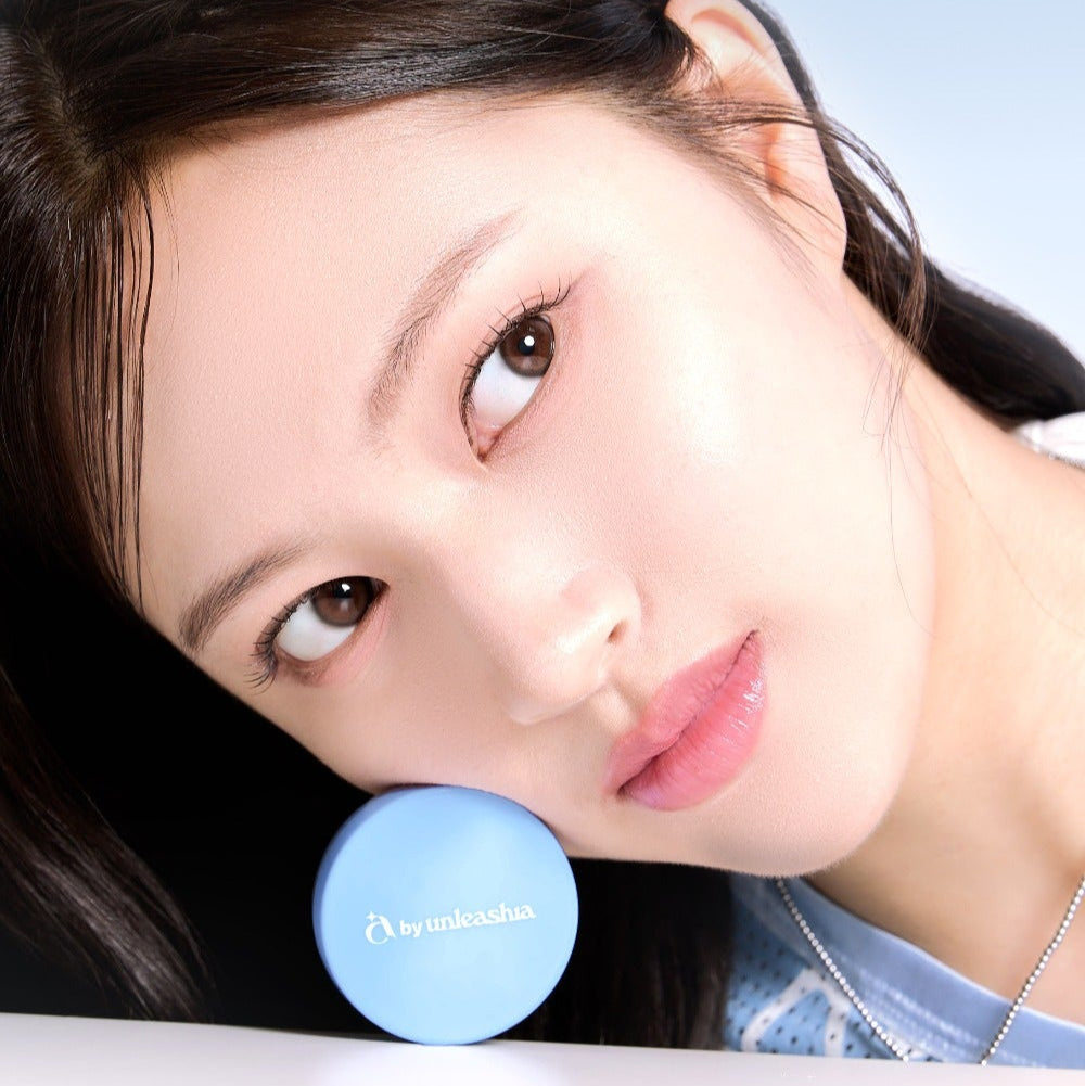 Woman with flawless skin holding UNLEASHIA Be Be Blue Cushion