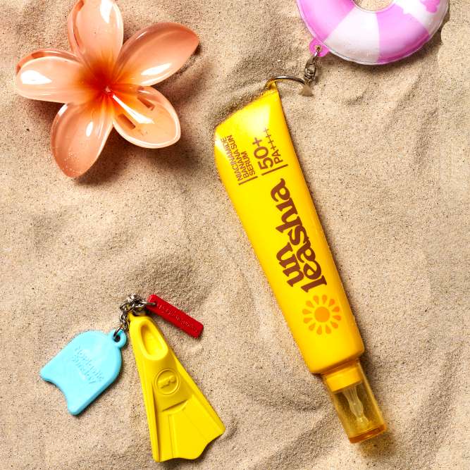 UNLEASHIA Niacinamide Banana Sun Serum 40ml tube on sandy beach with summer-themed accessories