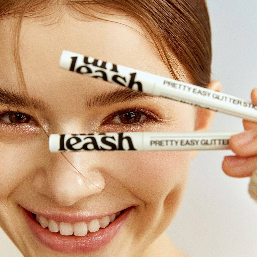 UNLEASHIA Pretty Easy Glitter Stick held by a smiling person showcasing the product's sleek design and glitter application.