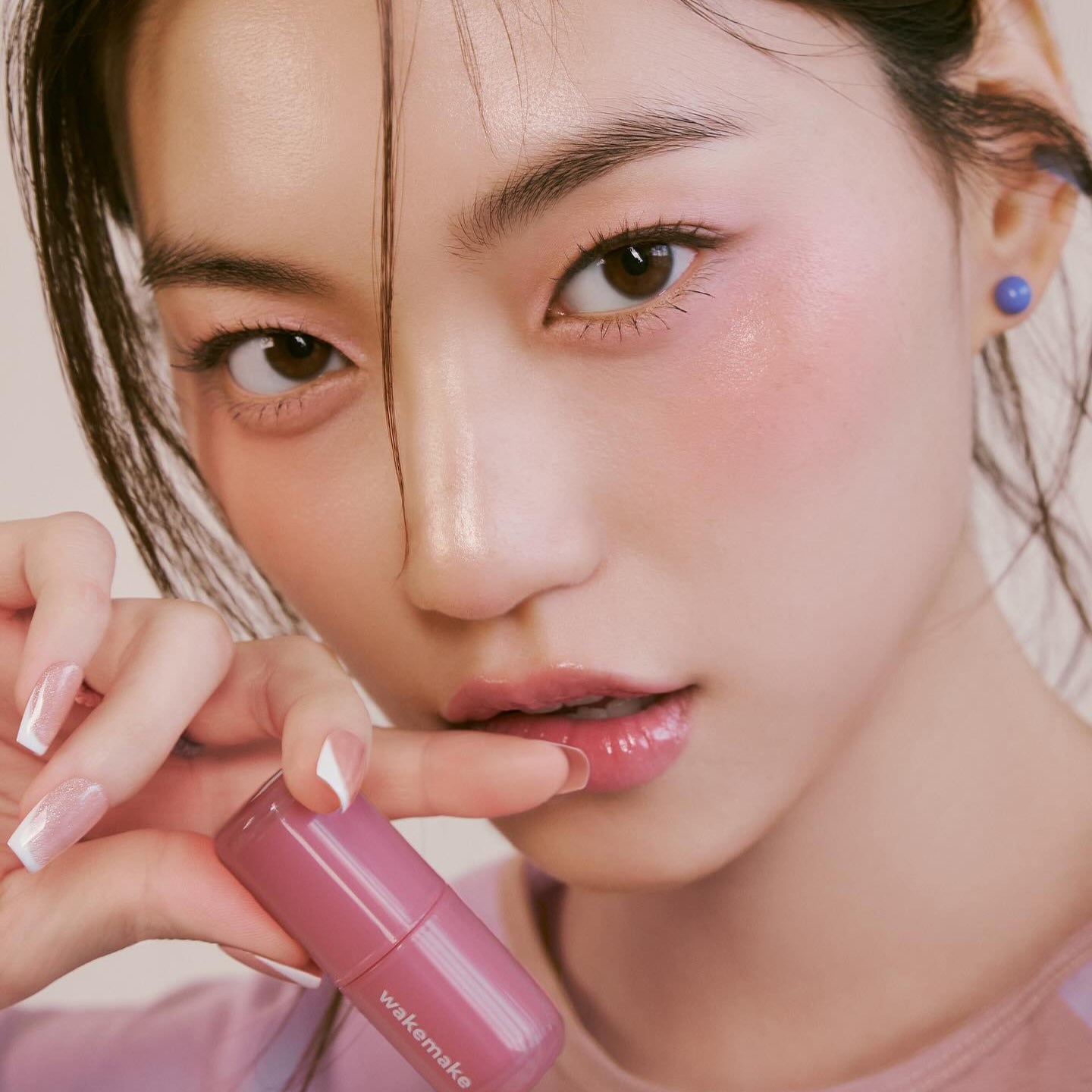 Model wearing pink shade of WAKE MAKE Waterfull Glow Tint 4.6g, showcasing vibrant and glossy lip color.