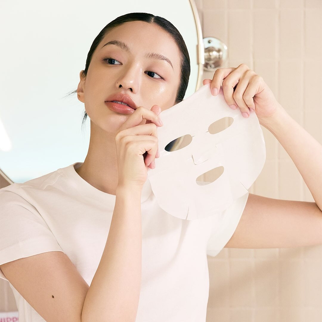 Woman holding WHIPPED Butter Vegan Glow Barrier Squeeze Mask 1ea ready to apply on face for skincare routine.