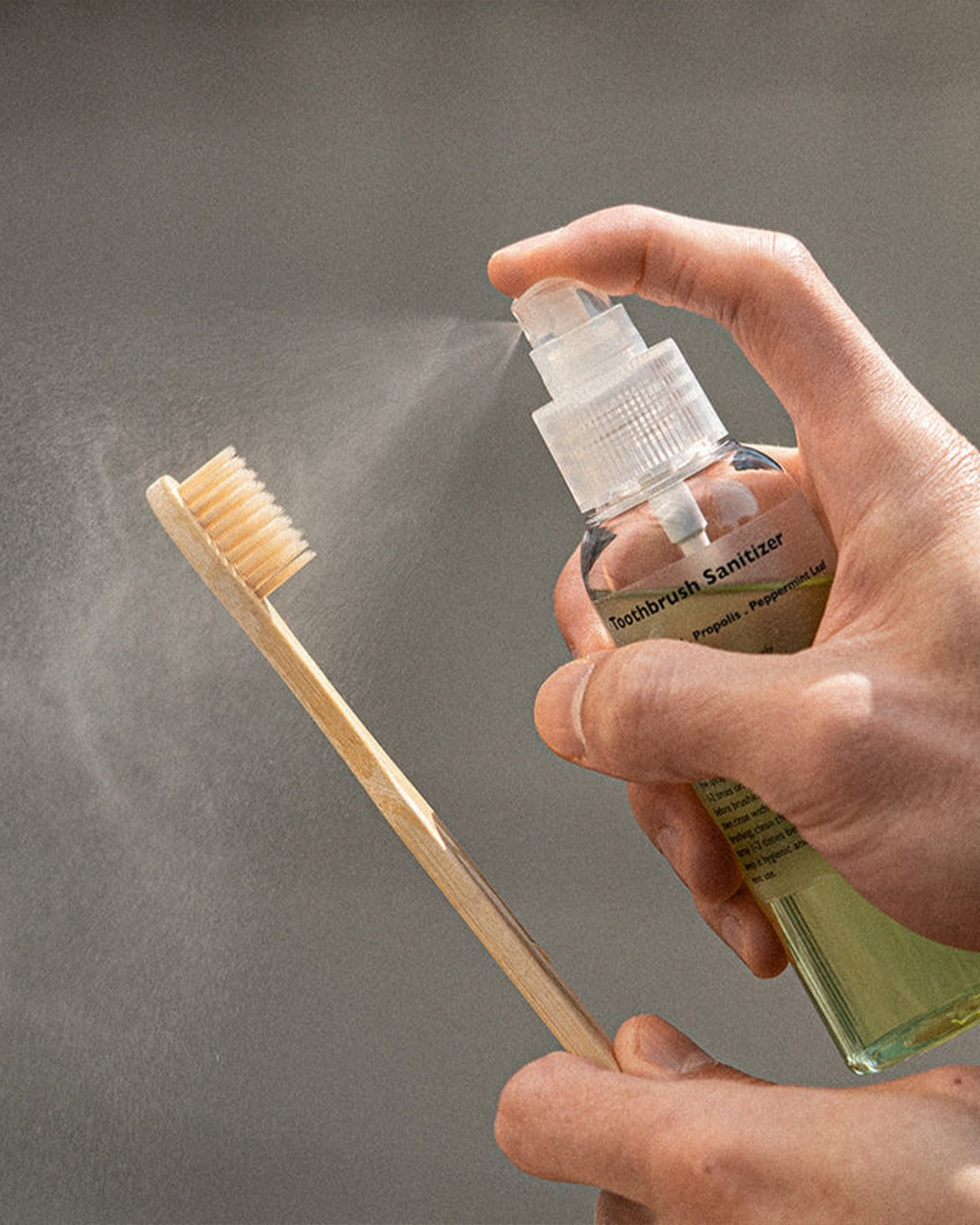 Spraying toothbrush sanitizer on wooden toothbrush for hygiene