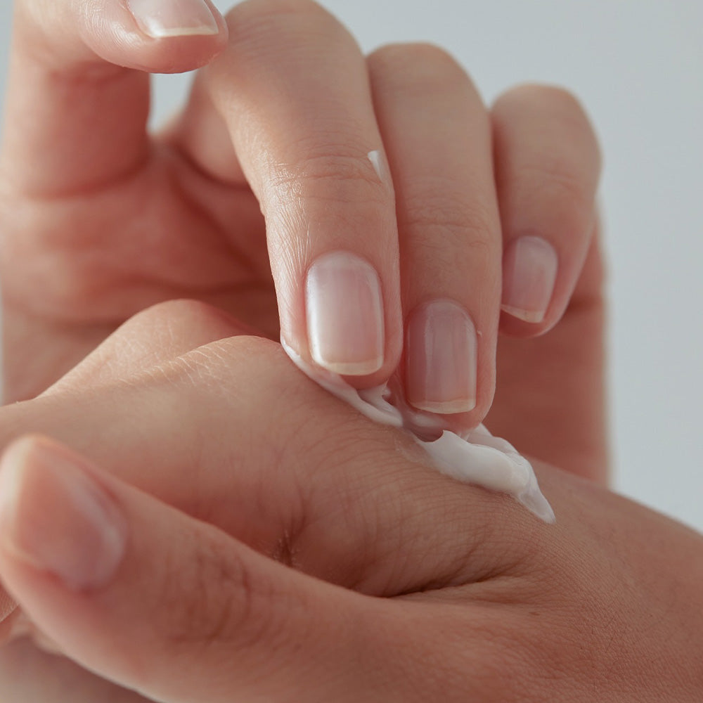 Close-up of hands applying moisturizing cream on skin for hydration and care.
