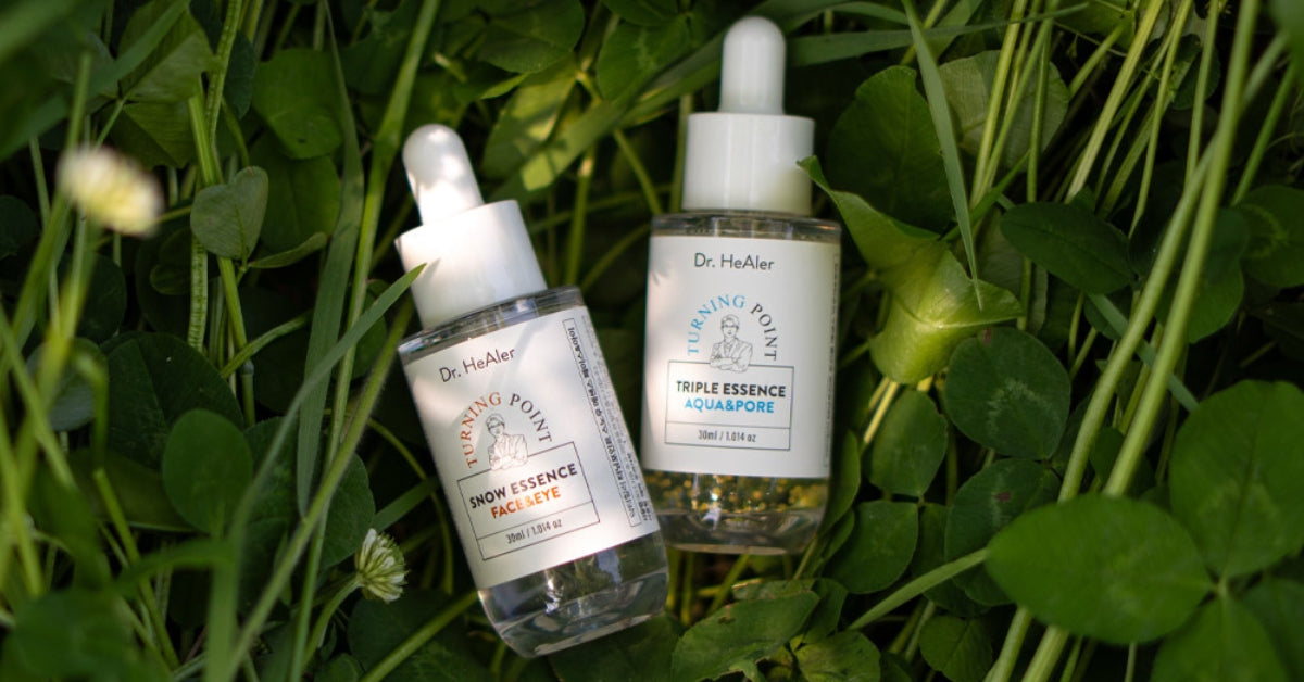 Discover the Magic of Dr. Healer: Your Skin’s Best Friend for Radiance and Revival! Two serum bottles nestled in green leaves.