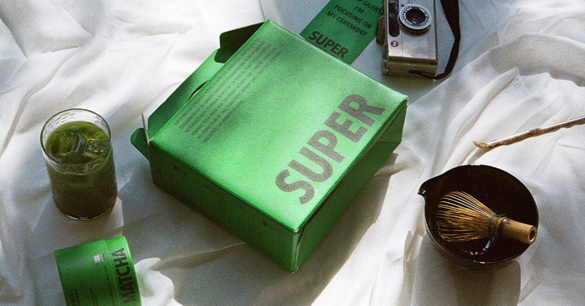 Hit the Tea SuperMatcha: The Ultimate Green Power Boost! packaging with matcha tools on a cloth background