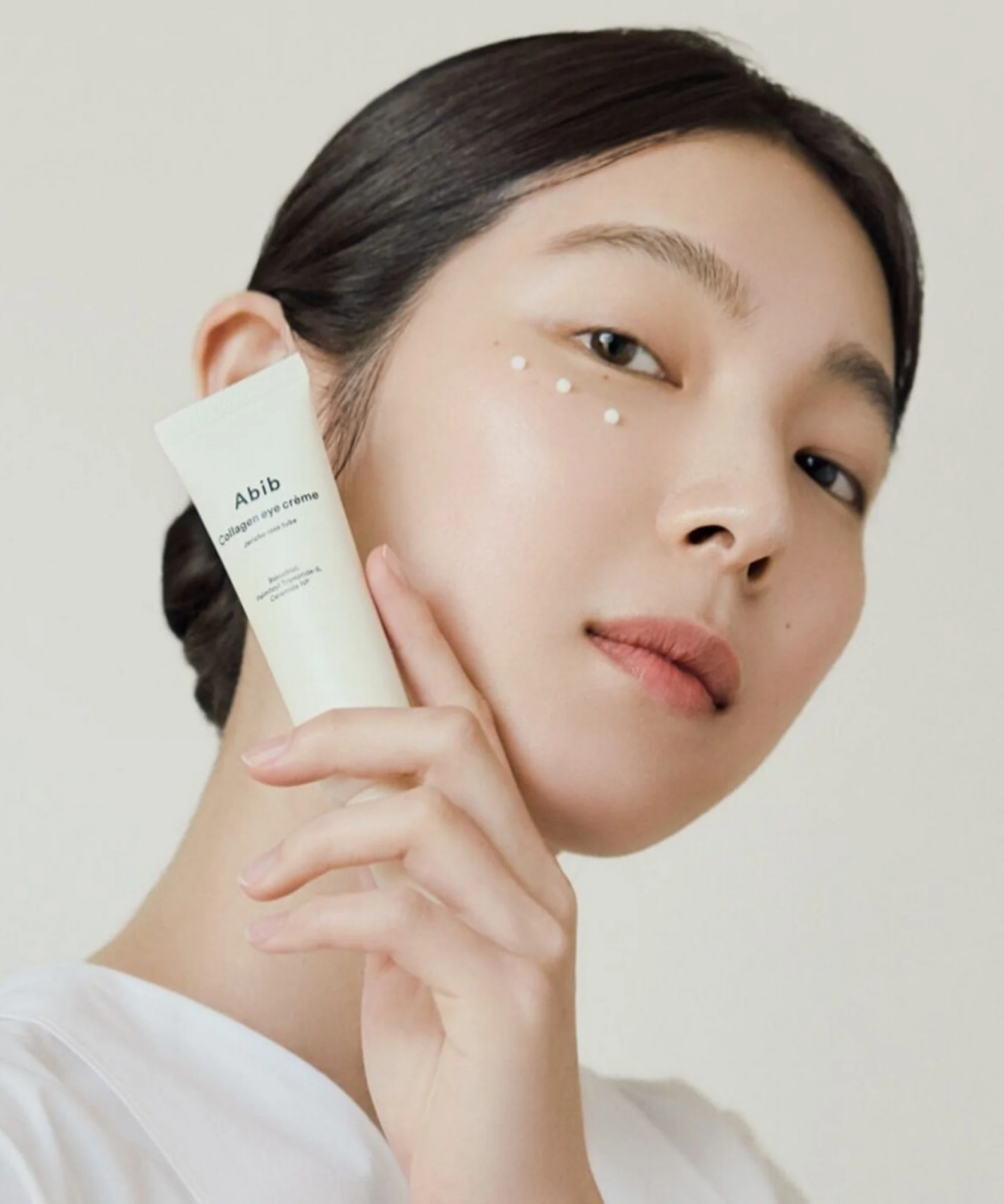 Model applying ABIB Collagen Eye Cream Jericho Rose Tube 30ml to skin