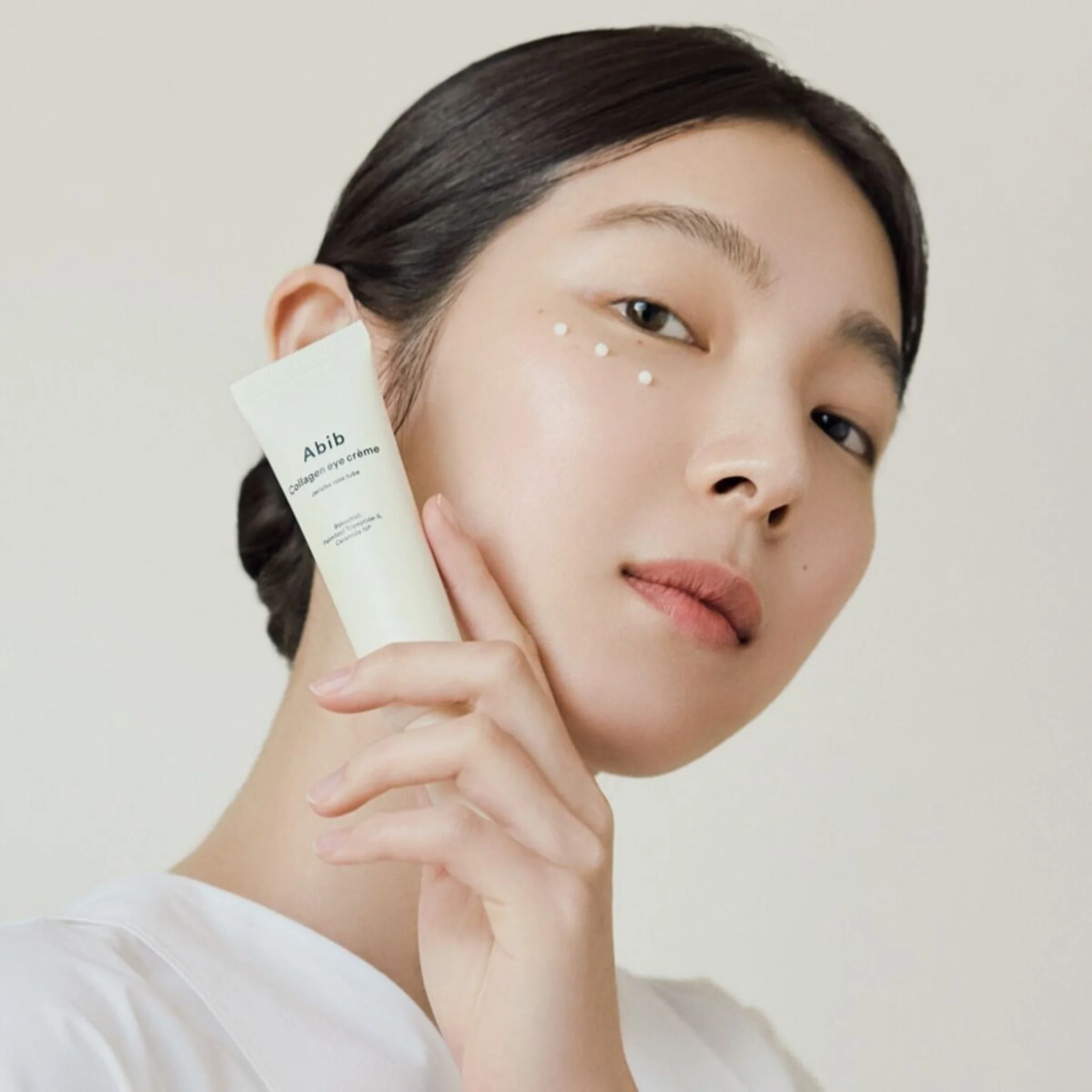 Model applying ABIB Collagen Eye Cream Jericho Rose Tube 30ml to skin