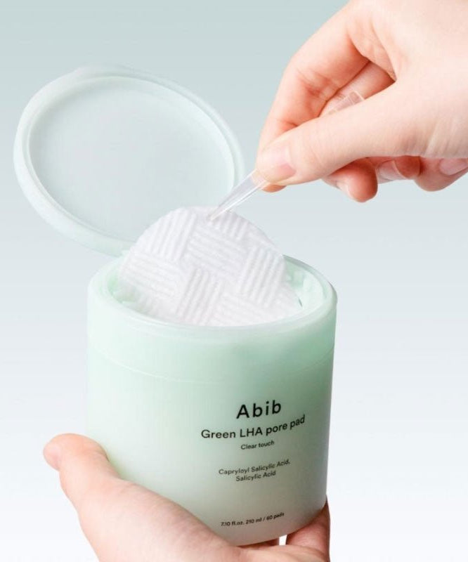 Close-up of a hand using ABIB Green LHA Pore Pad Clear Touch 60 Sheets for skincare routine