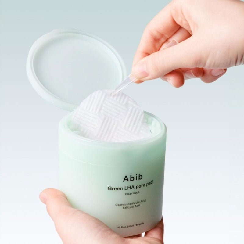 Close-up of a hand using ABIB Green LHA Pore Pad Clear Touch 60 Sheets for skincare routine