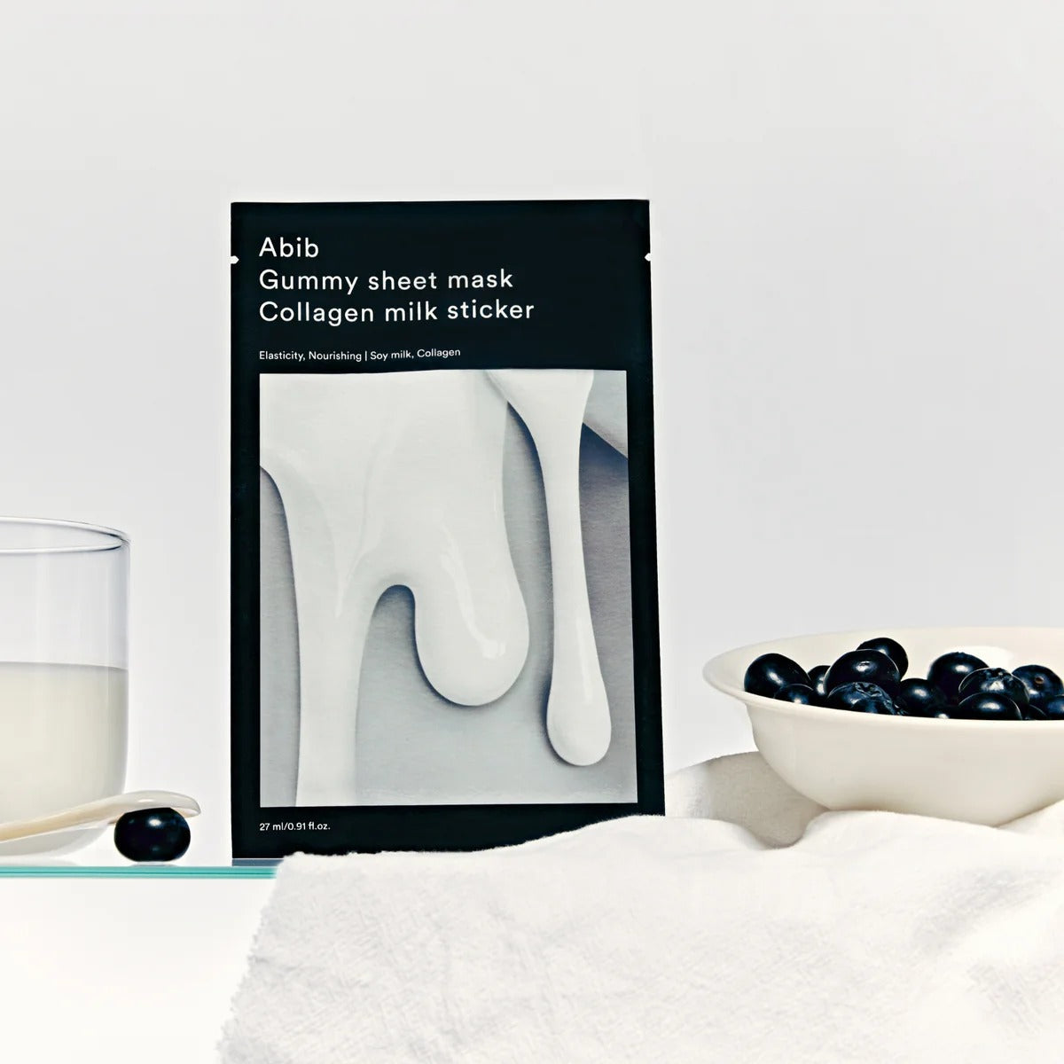 ABIB Gummy Sheets Mask Collagen Milk Sticker 10 sheets packaging next to a glass of milk and blueberries on a white background.