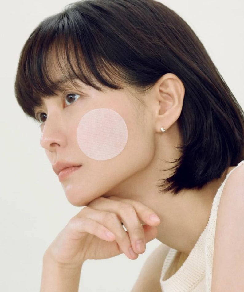 Woman using ABIB Heartleaf Spot Pad Calming Touch 70 pads on her face for soothing skincare treatment.